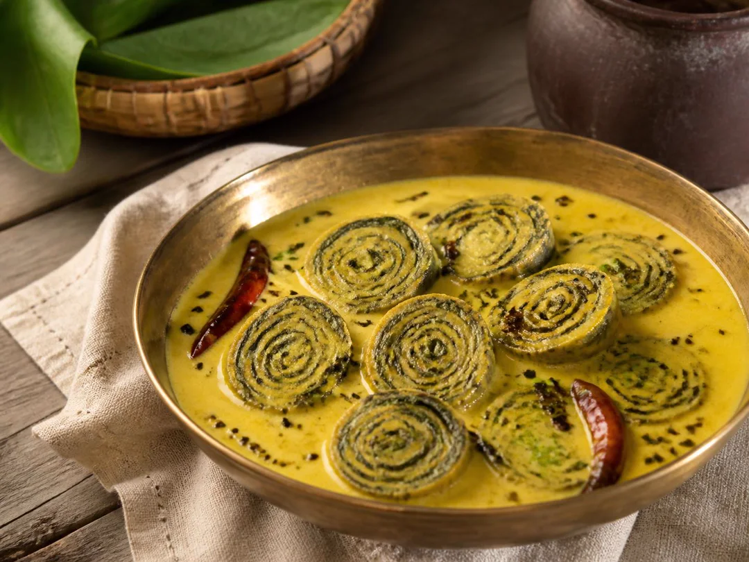 Colocasia Leaf Kadhi — Spiral colocasia leaf rolls in yellow yogurt and gram flour kadhi