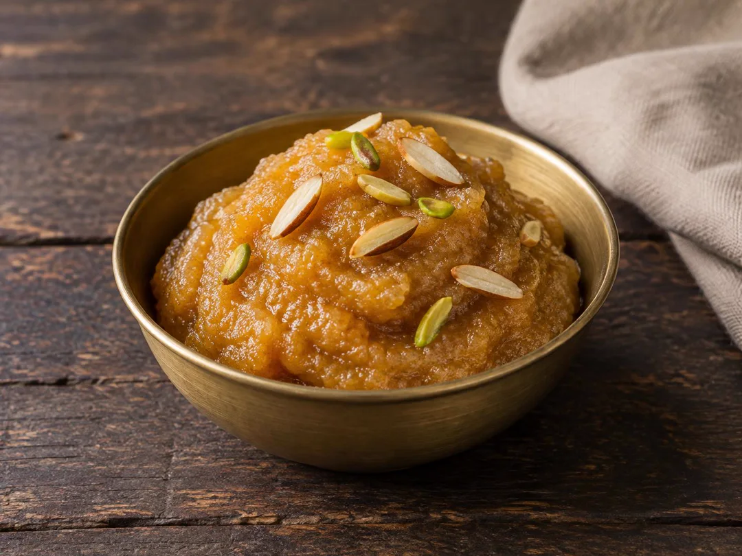 Badam Halwa — Dense amber-gold almond halwa with fine almond grain, ghee sheen and pistachio